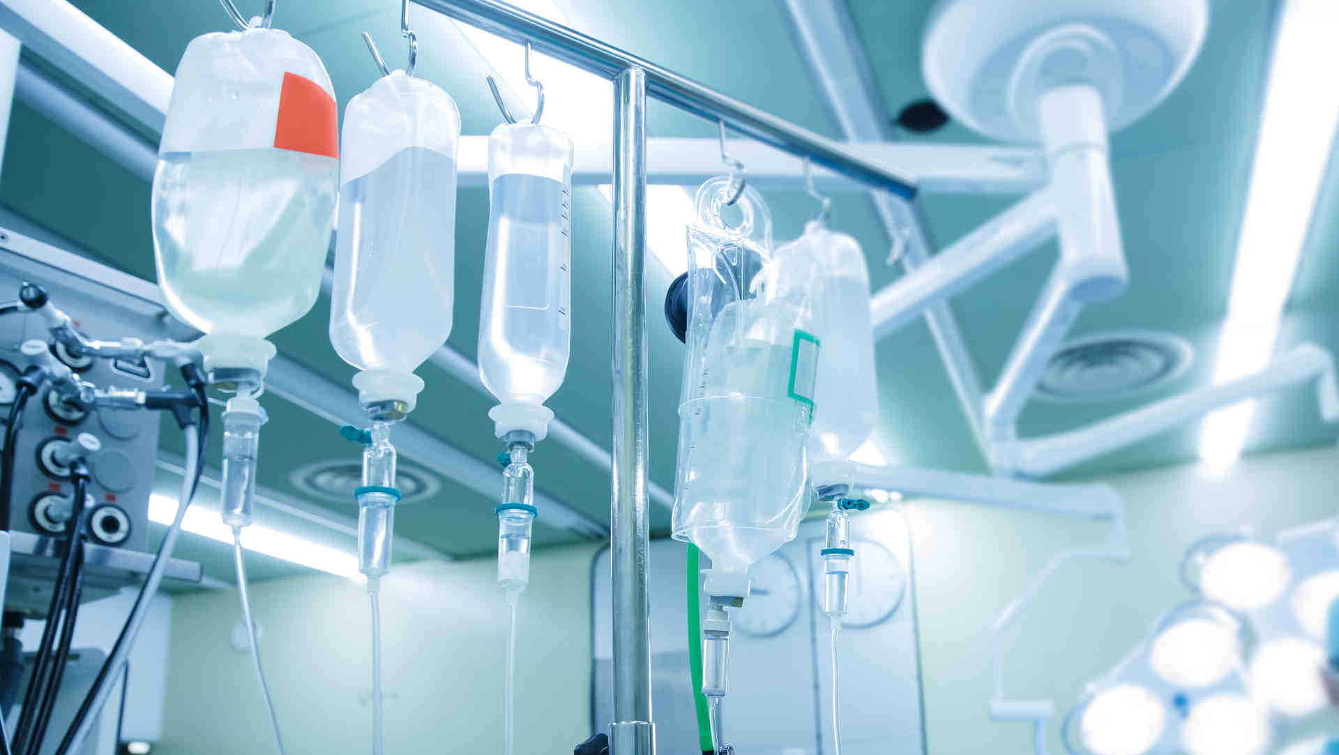 5 different IV fluid containers hanging in theatre
