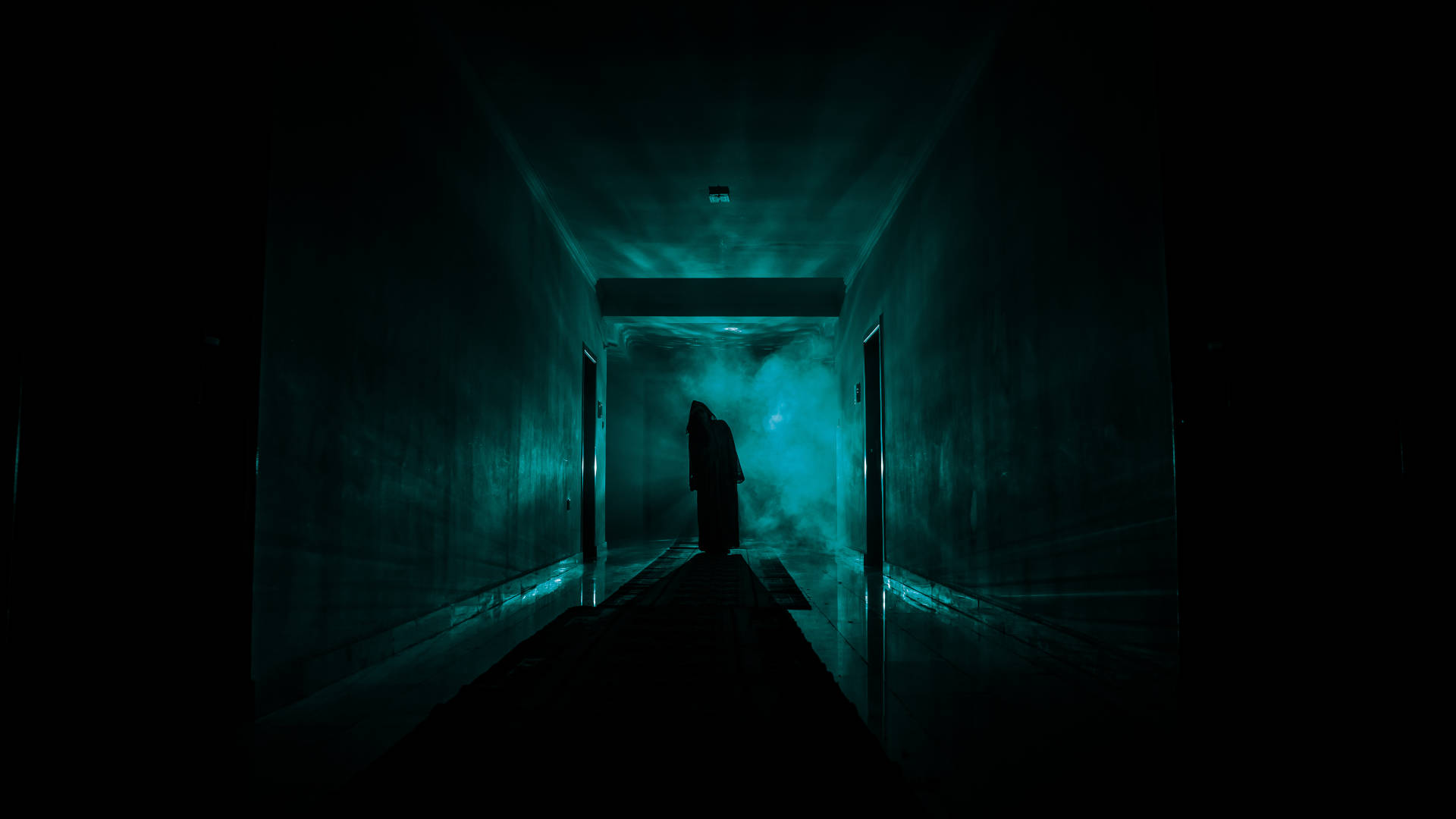 Person at the end of a long dark green-black corridor