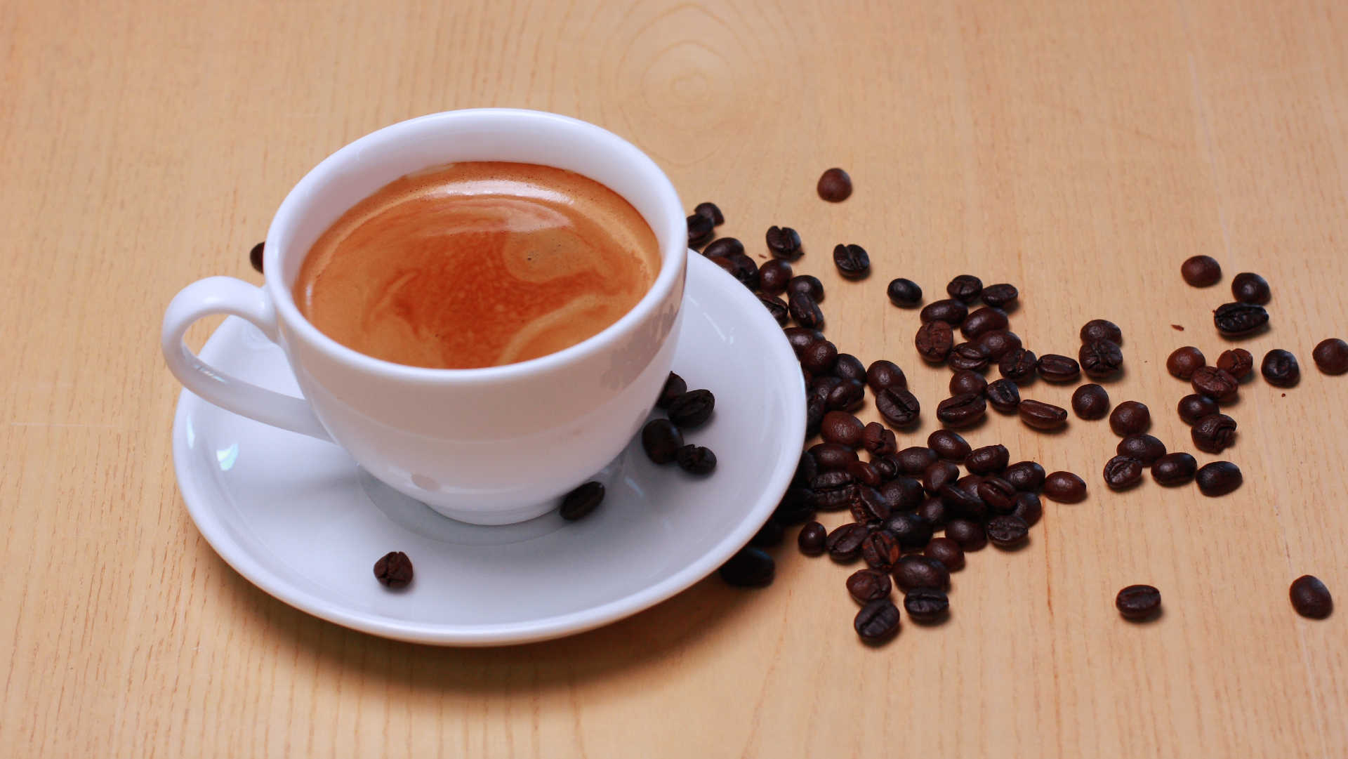 A cup of coffee with coffee beans alongside 