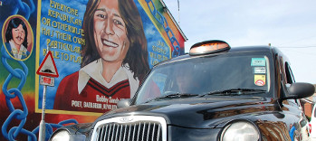 Black taxi against a Belfast mural